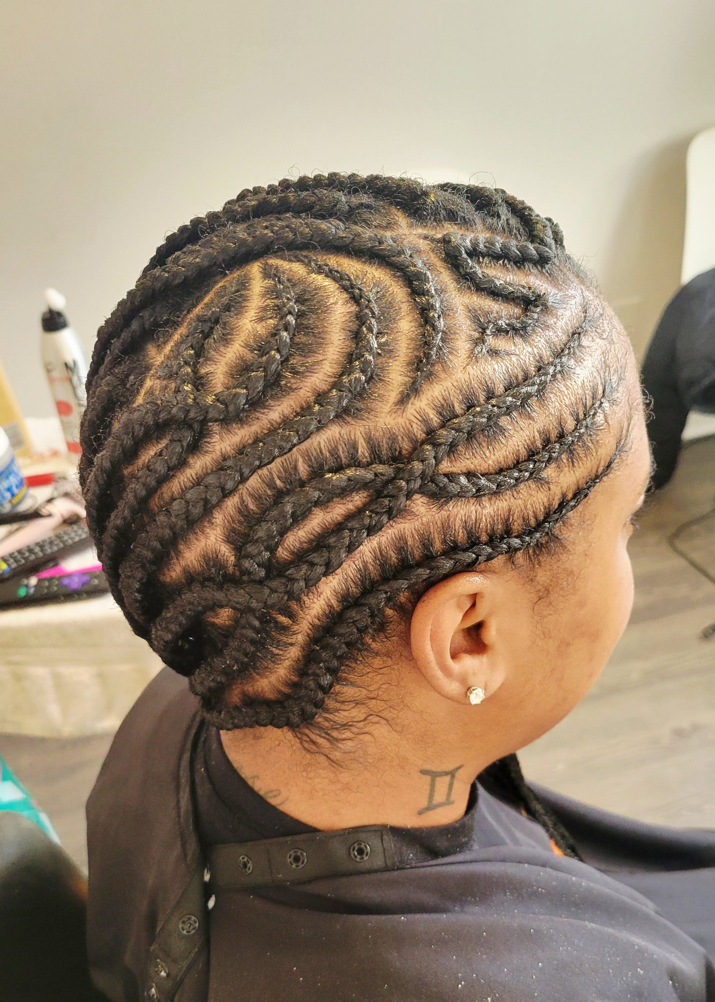 Close-up of zigzag feed-in cornrows with an intricate curved pattern, styled by Kristyna — side view