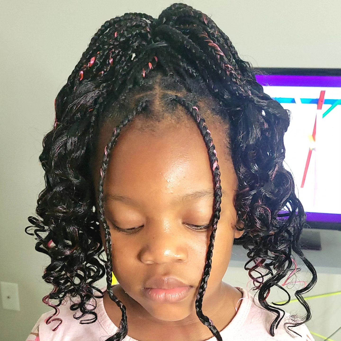 Kids boho braids with curly ends and pink highlights on a young girl, front view