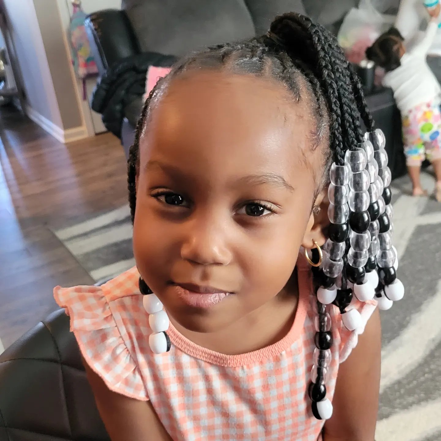 Kids braids with clear, black and white beads on a smiling young girl, front view