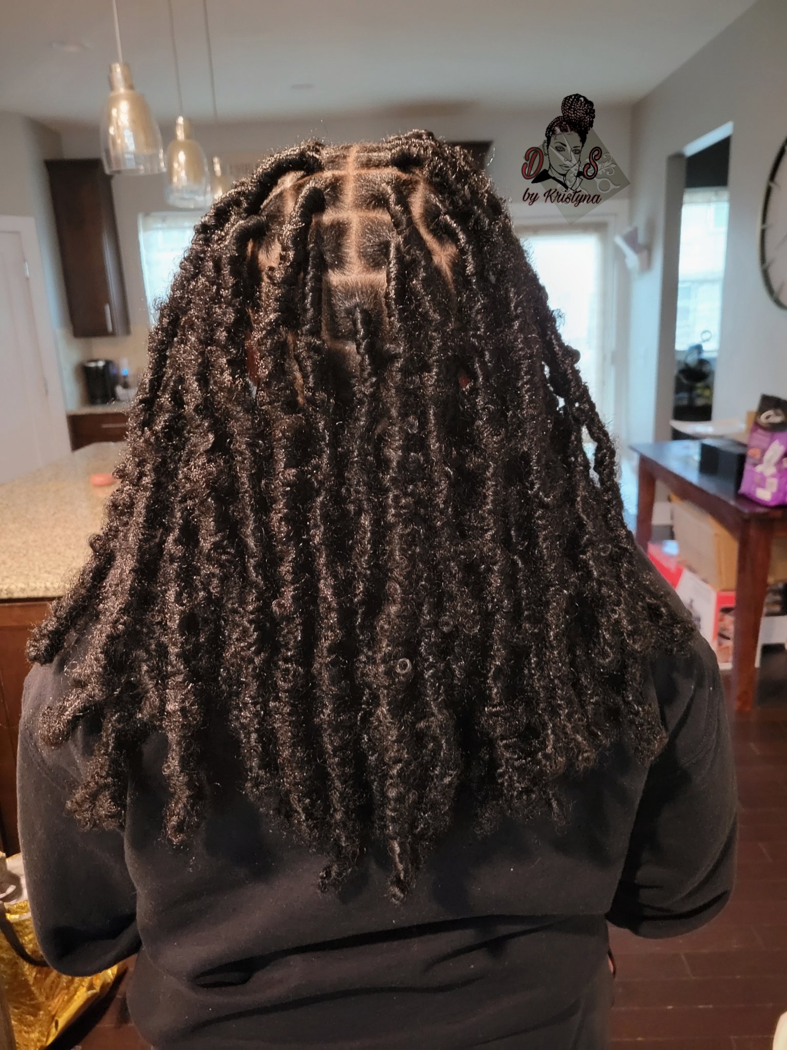 Butterfly locs in black, long and textured with neat square parts, back view