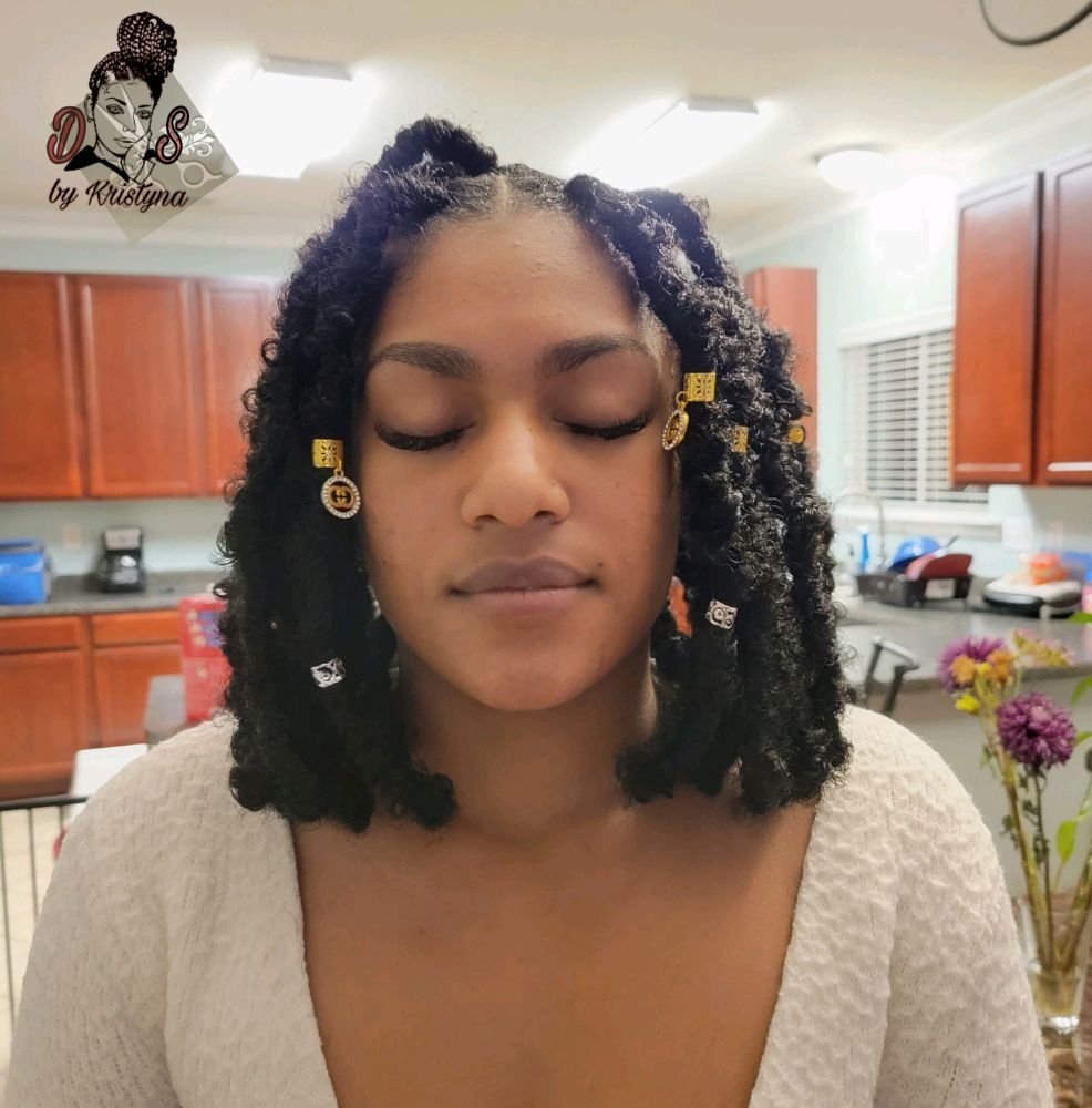 Butterfly locs in black styled in a short bob with gold cuffs and charms, front view